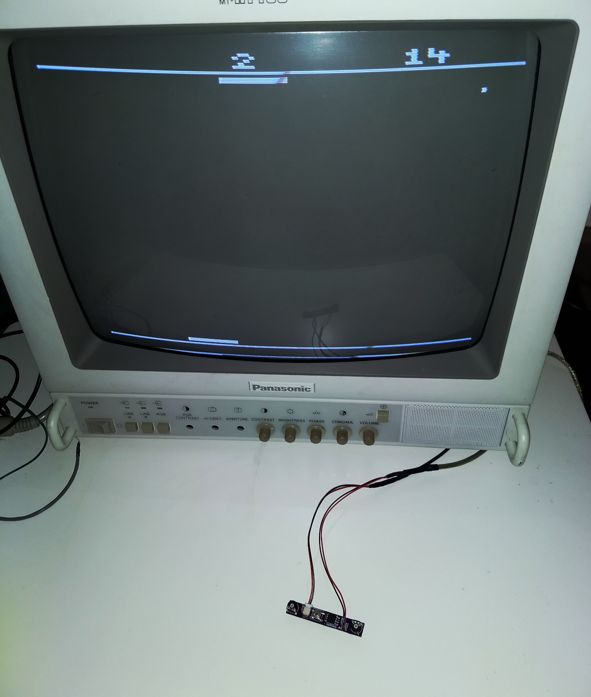 An old CRT video monitor with the circuit board attached to it. It shows a pong-like game.